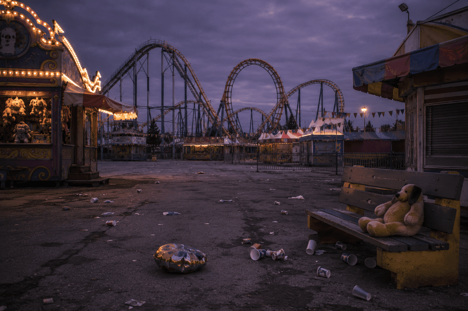 An empty amusement park at dusk, a roller coaster looming silently in the background